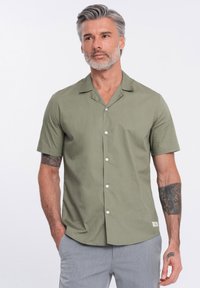 Kurzärmliges, knöpfbares Shirt aus Baumwolle in Salbeigrün, mit einem flachen Kragen, glatter Textur und weißen Knöpfen. Verfügt über ein kleines Etikett nahe dem Saum.