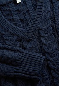 Navyblauwe kabelgebreide trui met een V-hals, geribde manchetten en gedetailleerde patronen, gemaakt van dikke garen voor warmte en textuur.