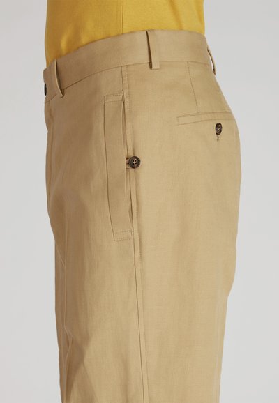 Pantalons en lin beige avec une texture lisse, dotés de poches latérales, d'une poche arrière avec un bouton et d'une taille ajustée.