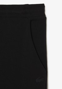 Zwarte sweatpants met een zachte stof, elastische tailleband, zijzakken en een subtiele reliëflogo op het onderste deel van het linkse been.