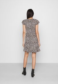 Sukienka w panterkę z krótkimi falbaniastymi rękawami, wcięciem w talii i rozkloszowanym dołem. Noszona z czarnymi botkami za kostkę. Jasne tło.