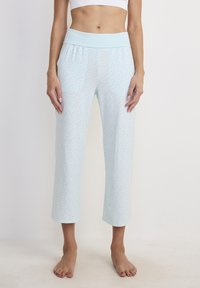 Pantaloni da pigiama azzurro chiaro con una fascia elastica larga in vita, caratterizzati da un sottile motivo a pois. Lunghezza cropped con una texture liscia.