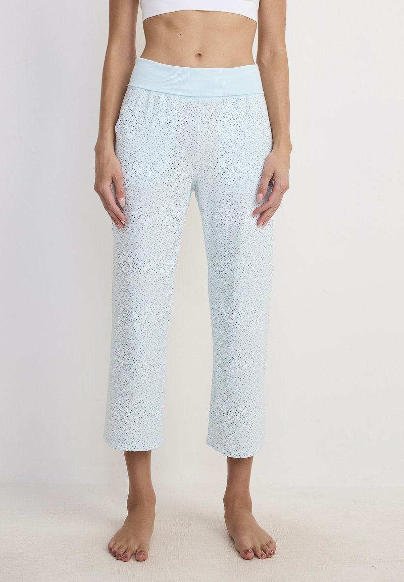 Pantaloni da pigiama azzurro chiaro con una fascia elastica larga in vita, caratterizzati da un sottile motivo a pois. Lunghezza cropped con una texture liscia.