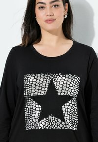 Zwarte longsleeve t-shirt met een grote zilveren stergrafiek op de voorkant, gemaakt van gestructureerde stippen en vierkantpatronen.