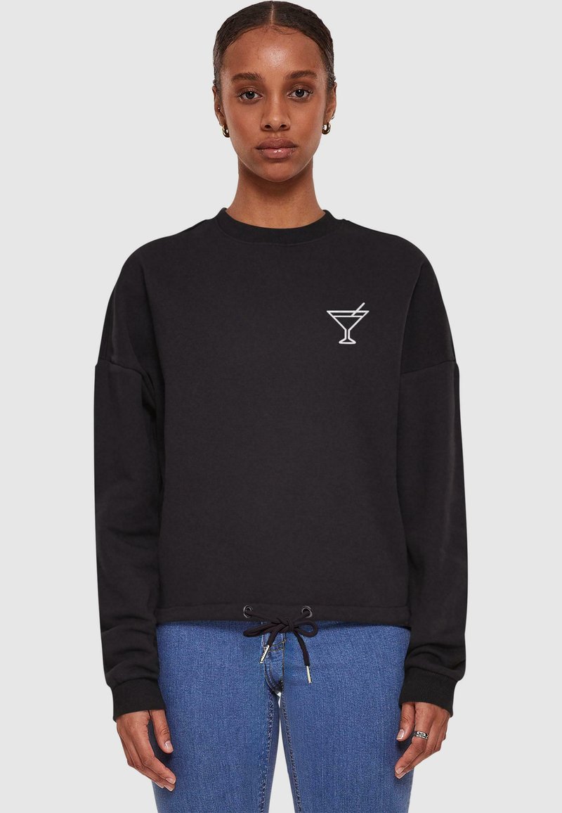 Svart sweatshirt med långa ärmar, rundad halsringning och dragsko i nederkant; har en vit cocktailglasgrafik på bröstet.
