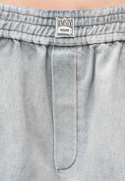 Svetlomodré rifľové šortky majú elastický pás a stredový záhyb s kontrastným šitím. Štítok nesie nápis "MM6 Maison Margiela".