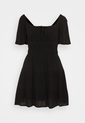 Mustre must pikkade hõljuvate varrukatega must kleit, madala kaelusega, nöördetailidega ja astmelise, voolava seelikuosa. Valmistatud kergest kangast.