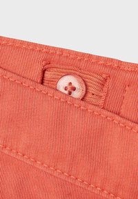 Tissu de couleur corail avec un tissage texturé, présentant une fermeture à bouton. Les détails de couture sont visibles le long du bord de la poche.