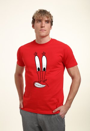 Red cotton t-shirt featuring a cartoon character's face with large white eyes, a smiling mouth, and two antenna-like accents on top.