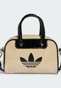Beige faux leather bag with a shiny black patent trim and handles. Features a prominent black Adidas logo on the front and a zip closure.