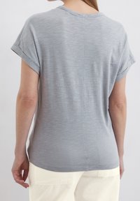 Szary t-shirt z krótkim rękawem, z podwiniętymi mankietami, o miękkiej teksturze i delikatnym melanżowym wzorze, posiadający prosty szew na plecach oraz luźny krój.