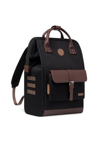 Sac à dos avec un corps en tissu noir, des accents en cuir marron, des poignées supérieures, une poche avant à rabat et trois bandes horizontales sur le côté.