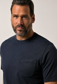 Námořnicky modré tričko s krátkým rukávem vyrobené z bavlny, s náprsní kapsou a kulatým výstřihem. Hladký povrch a standardní střih.