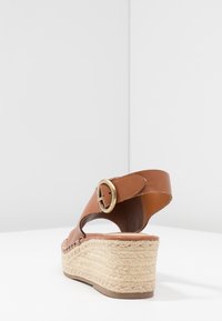 Sandale compensée en cuir marron avec détail à boucle, plateforme en jute tissé, bout rond et finition lisse.