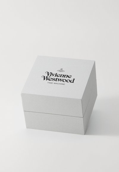 Pelēks kvadrāts kartona kastē ar slēgšanas vāku, kurā uz augšas ir teksts "Vivienne Westwood TIME MACHINE" melnā fontā.
