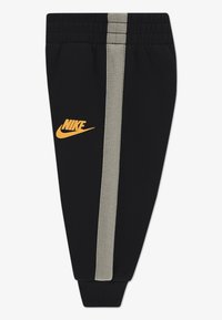 Crne jogger hlače napravljene od mekog materijala, s narančastim Nike logom i sivom prugom sa strane. Elastična pojas i manžetne.