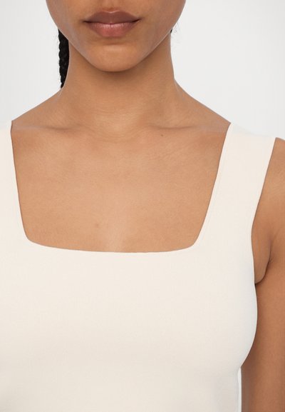 White square-neck tank top with broad straps, made from a soft, stretchy fabric. Smooth texture, form-fitting design, minimalistic style.