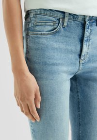 Jasnoniebieskie dżinsy o slim fit, z pięcioma kieszeniami, subtelnymi detalami wyst ibienia oraz gładką fakturą.