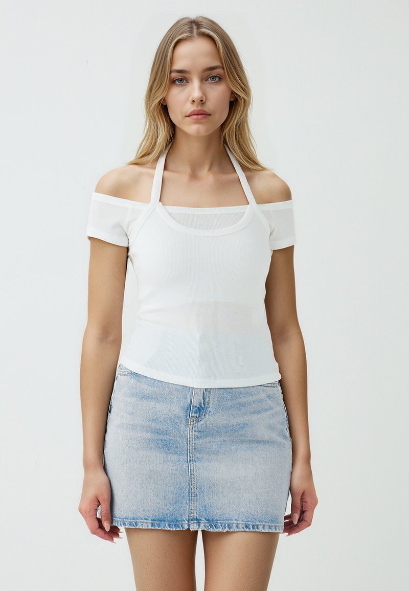 Biały prążkowany top crop z off-the-shoulder, połączony z jasnoniebieską mini spódnicą dżinsową z nieco przetartym wykończeniem.
