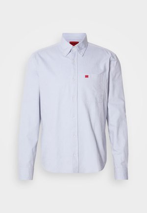 Světlomodrá košile na knoflíky z látky s hladkou texturou. Na náprsní kapse je malé červené logo a košile má límeček s knoflíčky.