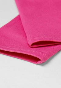 Chaussettes fuchsias avec une texture côtelée et des bords cousus, pliées soigneusement pour afficher la surface lisse et la couleur éclatante.