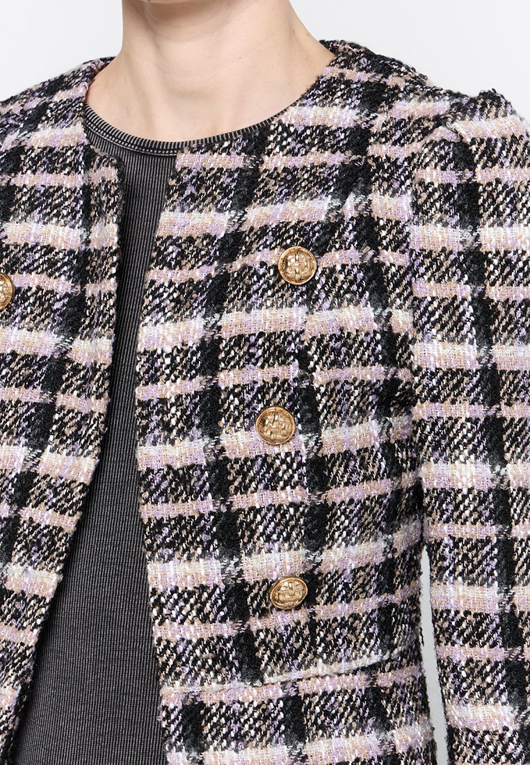 Chaqueta de tweed con un patrón de cuadros en negro, morado y blanco, que presenta botones dorados y un escote redondo para un diseño estructurado.