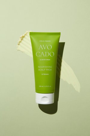 Tube verte de "Avo Cado Nourishing Scalp Pack," avec un couvercle à charnière blanc et un accent banane, sur un fond vert clair.