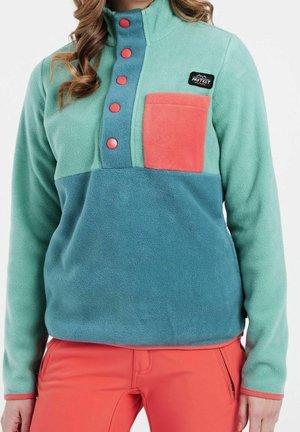 Pull-over en polaire de couleur teal et vert menthe, avec une poche poitrine corail, cinq boutons contrastants et un col haut.