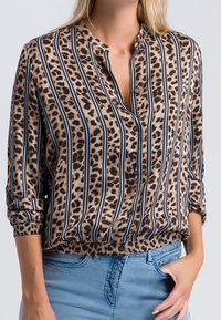 Tijgerprint blouse met verticale blauwe strepen, lichtgewicht stof, kraaghals, en gerimpelde zoom. Voorzien van knopen aan de voorkant en opgerolde mouwen.