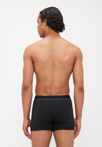 Schwarze Boxershorts aus glattem Stoff, mit körperbetonter Form, elastischem Bund und minimalistischem Design ohne sichtbare Muster.