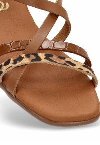 Sandalias marrones con tiras, de acabado en cuero suave, con una tira de estampado de leopardo y una suela plana y texturizada.