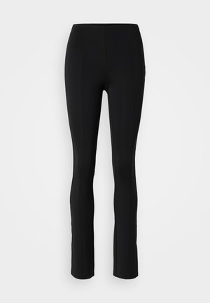 Leggings neri realizzati in materiale elastico, con una silhouette aderente, vita media e dettagli delle cuciture lungo la parte anteriore e posteriore.