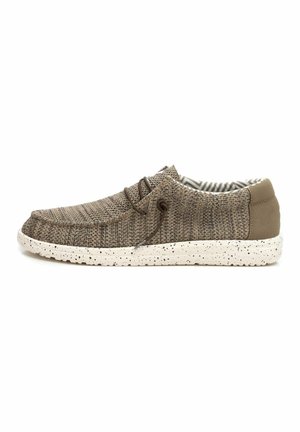 Zapatilla marrón con textura, con parte superior de tela, puntera redonda y diseño de cordones. Suela blanca moteada y forro interior a rayas.