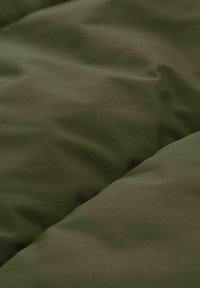 Tkanina w oliwkowym kolorze, wyściełana, o gładkiej fakturze z miękkimi fałdami i delikatnymi krzywiznami, zaprojektowana z myślą o izolacji i komforcie.