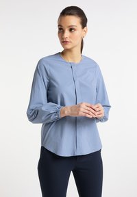 Jasnoniebieska, długi rękaw, bluzka z okrągłym dekoltem, zebranymi mankietami i projektem zapięcia z przodu. Gładka tekstura i luźny krój.