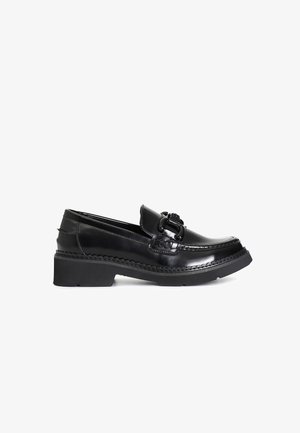 Black patent leather loafers with a round toe, a braided accent, and a chunky black rubber sole. Smooth texture and sleek design.