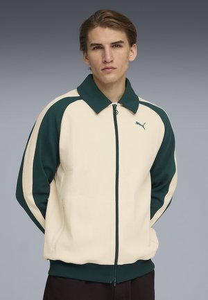 Puma zip-up jacka i beige med mörkgröna accenter. Har en ribbad krage, sidofickor och en logotyp på bröstet. Texturerat tyg.