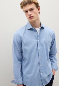 Camicia celeste a maniche lunghe in tessuto morbido. Presenta un colletto classico, maniche lunghe e bottoni bianchi sul davanti.