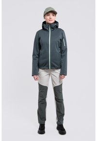 Dunkelgrüne Softshelljacke für Herren mit hellgrünem Reißverschluss, kombiniert mit hellgrauen Hosen mit dunkelgrünen Akzenten und durchgehenden Reißverschlusstaschen.