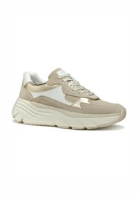 Zapatilla de ante y malla en beige y blanco, con una suela gruesa y texturizada, puntera redonda y cordones grises con acentos metálicos.