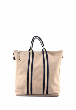 Sac fourre-tout beige texturé avec des poignées rayées bleu marine et blanc et un petit curseur de fermeture éclair avec un charm rouge, blanc et vert.