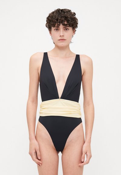 Costume intero nero con scollatura a V profonda, dettaglio in vita arricciato giallo e gambe a taglio alto. Tessuto liscio e design minimalista.
