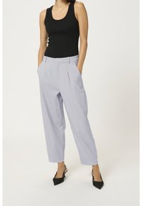 Jasnoszare spódnice plisowane z bocznymi kieszeniami, dopasowany krój, połączone z czarnym topem na ramiączkach w prążki i czarnymi czółenkami w szpic.