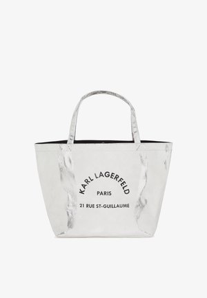Sac cabas argenté avec deux poignées, avec texte noir « Karl Lagerfeld Paris 21 Rue St-Guillaume » sur le devant.