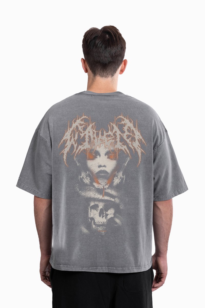 Grå oversized t-shirt med et stort grafisk design på bagsiden, der viser et ansigt, kranier og slangeelementer i kontrastfarver.