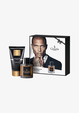 Le set Gisada Ambassador comprend un tube de gel douche noir, une bouteille de parfum en verre brun et un emballage en boîte présentant un modèle et le logo de la marque.