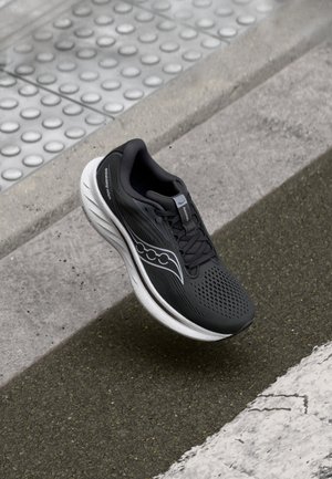 Black running shoe with a mesh upper, textured detailing, and white sole. Features include a lace closure and logo accent on the side.