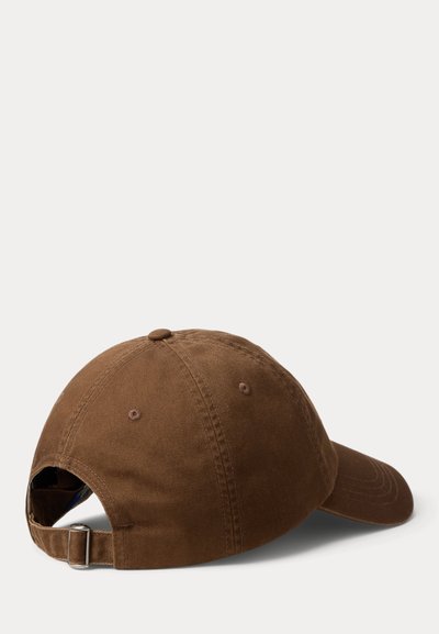 Καφέ βαμβακερό καπέλο με κυρτό γείσο, ρυθμιζόμενο λουράκι στο πίσω μέρος και διακοσμητικές ραφές στο πάνω μέρος. Υφασμάτινη υφή με ομοιόμορφο χρώμα.