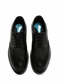 Chaussures habillées en cuir noir avec une finition texturée, design à bout à ailes, détails perforés et semelles intérieures bleues. Bout arrondi et semelle plate.