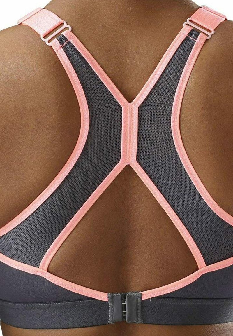 Reggiseno sportivo nero con pannelli in rete, caratterizzato da dettagli rosa e design racerback. Spalline regolabili con chiusura a gancetto sul retro.